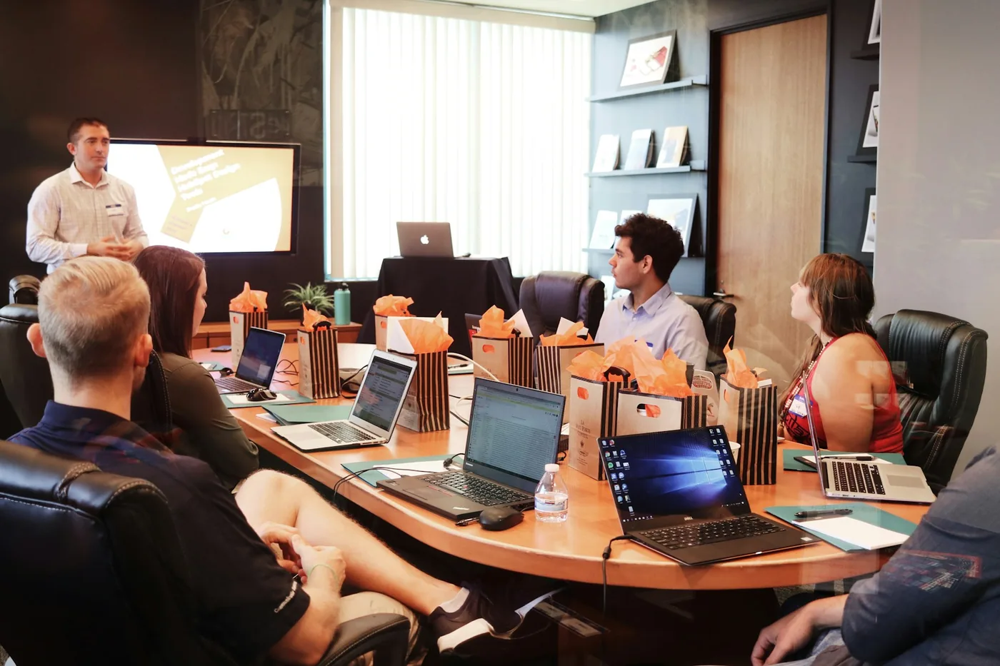 A facilitator leading a discussion with a group of professionals around a table